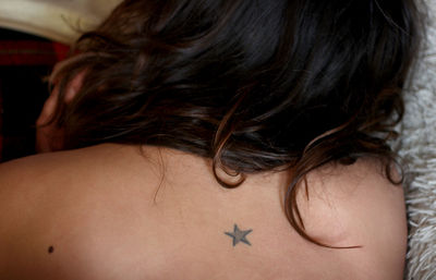 Rear view of woman with star shape tattoo on back