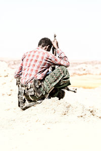 Rear view of man sitting on beach