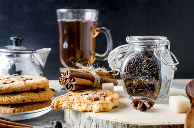 Close-up of ingredients by cookies and cinnamons in jar on cutting board