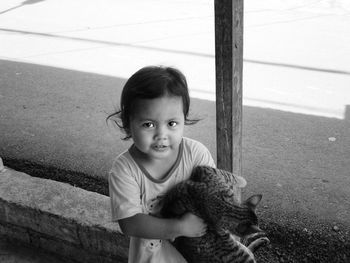 High angle view of boy looking away, little girl holding a pet cat