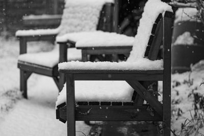 Empty bench in snow covered park during winter