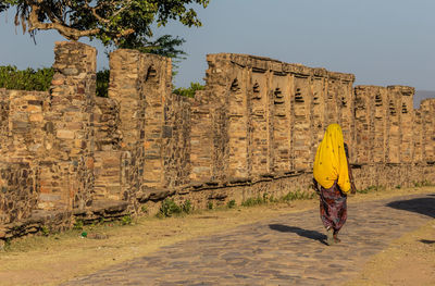 Full length rear view of woman against old building