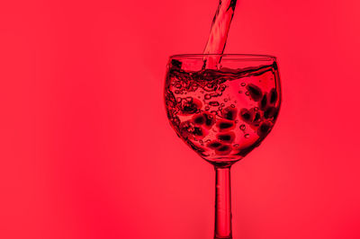 Close-up of wine glass against red background