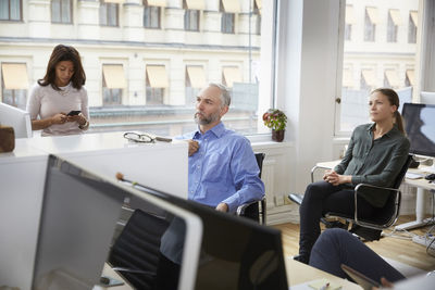 Male and female professionals are listening in meeting at office