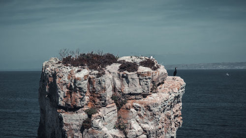 Rock formation by sea against sky