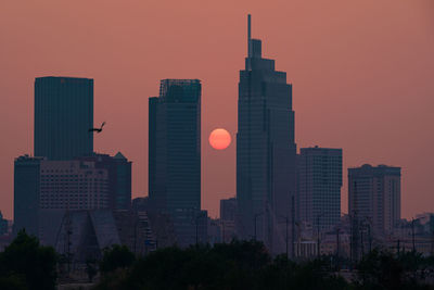 Skyscrapers in city against sky during sunset