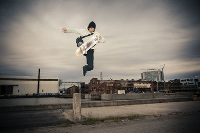 Male skateboarder jumping against sky at dusk