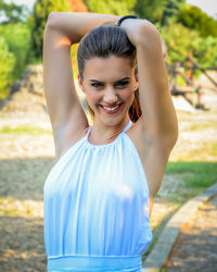 Portrait of happy woman with hands behind back standing on field