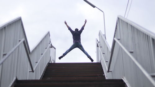 Low angle view of man jumping against built structure