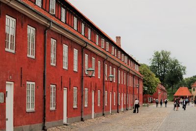 People walking on street by building against sky