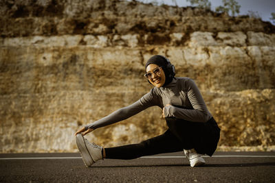 Portrait of young woman sitting on footpath