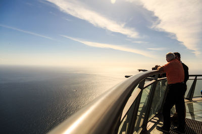 Rear view of man looking at sea against sky