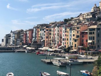 Buildings by sea in city against sky