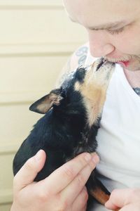 Close-up of dog licking man lips at home