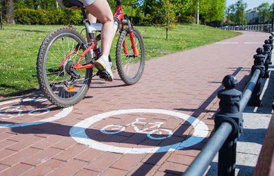 Low section of woman riding bicycle on lane