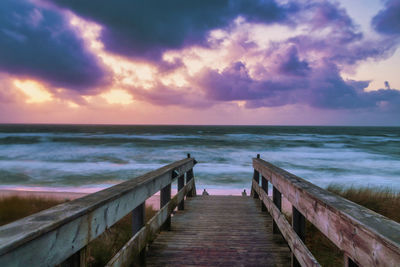 Pier over sea against sky during sunset