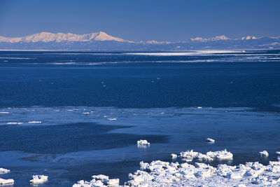 Scenic view of sea and snowcapped mountains against sky