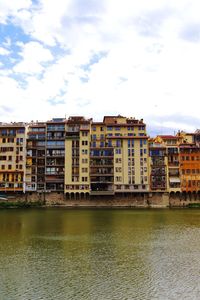 Buildings by river against sky