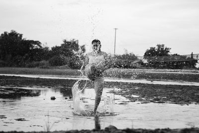 Man splashing water in lake against sky