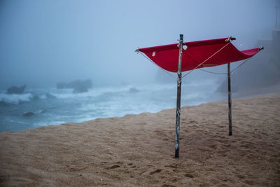 Red umbrella on beach against sky