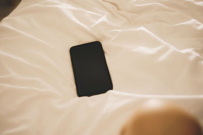 High angle view of mobile phone on bed