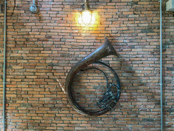 Low angle view of electric lamp on brick wall