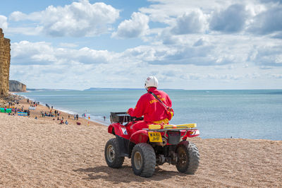 Rear view of man on beach against sky