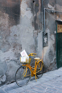 Bicycle parked on footpath against building