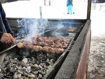 Close-up of person preparing food on barbecue grill