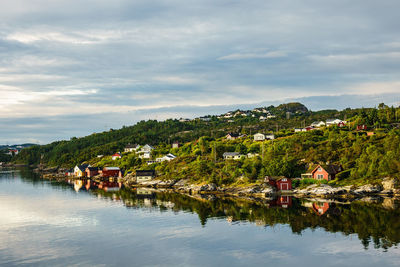 Scenic view of lake by houses against sky