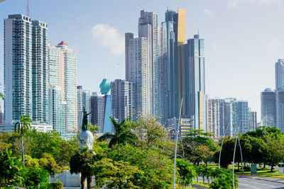 Monument to vasco nunes de balboa between trees and skyscrapers in  the city of panama