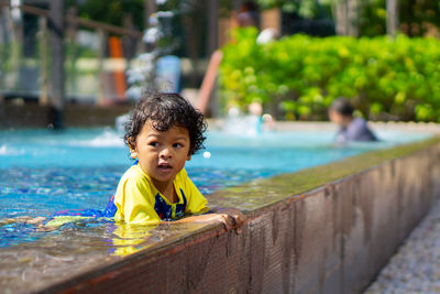 Cute boy looking away while swimming in pool