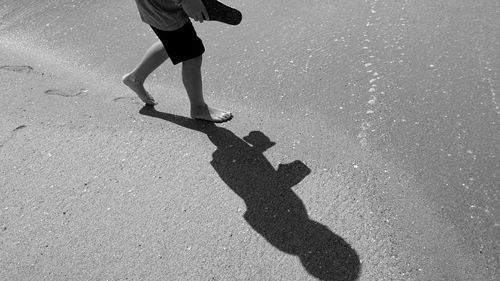 Low section of boy walking on sand at beach