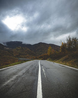 Road leading towards mountains against sky