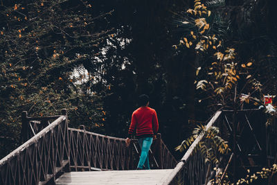 Rear view of woman walking on footbridge