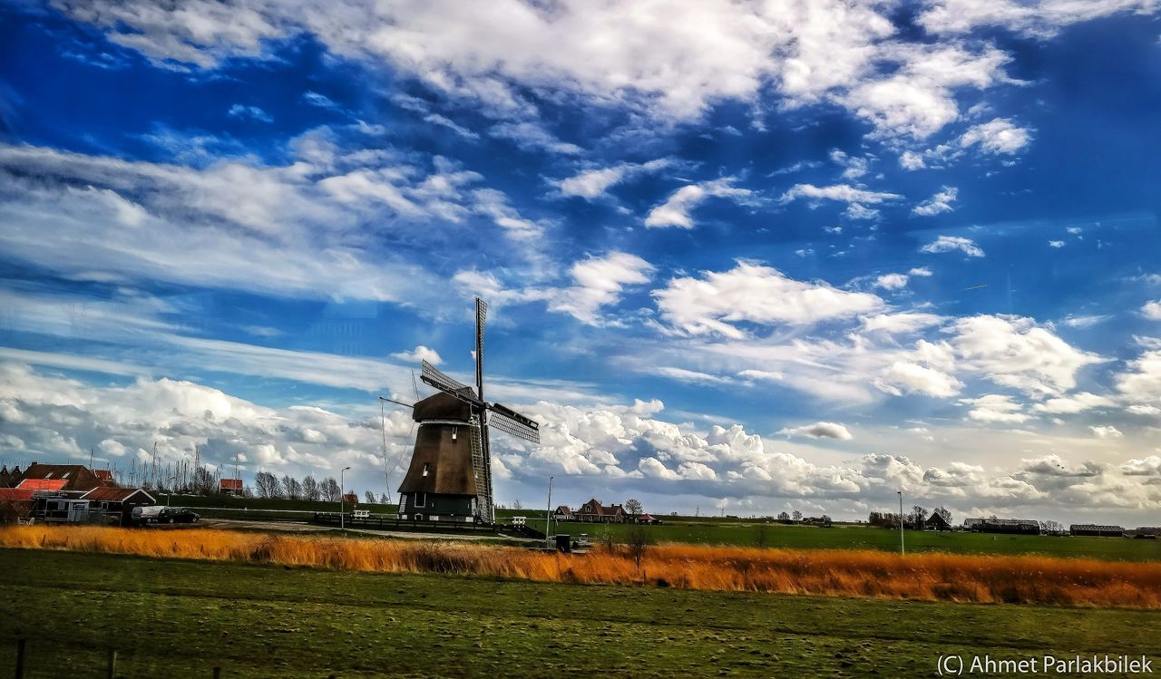 sky, field, landscape, wind power, building exterior, cloud - sky, built structure, rural scene, renewable energy, architecture, alternative energy, windmill, wind turbine, environmental conservation, traditional windmill, fuel and power generation, cloud, agriculture, grass, religion