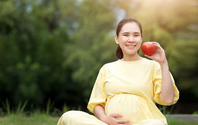 Portrait of a smiling young woman holding plant