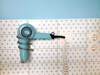 Blue vintage hair dryer at pattern wall