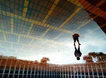 Low angle view of man jumping in city against sky