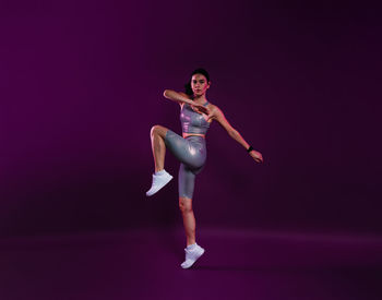 Full length of young woman jumping against black background
