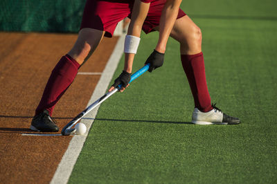 Low section of player playing hockey on field