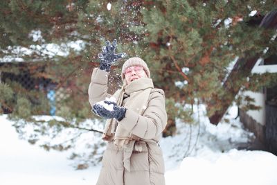 Woman playing with snow on field