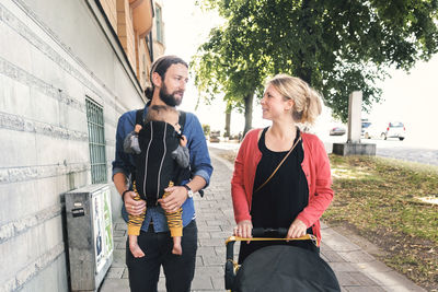 Mid adult parents with baby boy and stroller walking on sidewalk