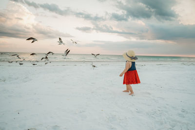 Rear view of woman on beach against sky