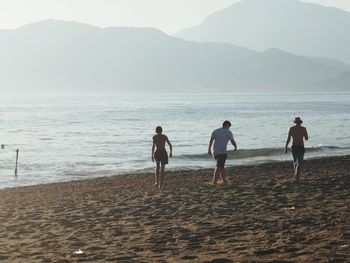 Rear view of people on beach against sky