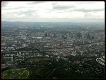 Aerial view of cityscape against cloudy sky