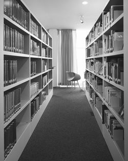 Empty chair amidst bookshelves in library