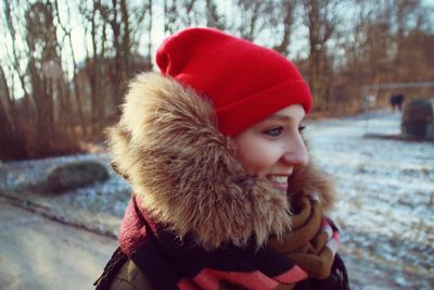 Portrait of young woman standing against trees