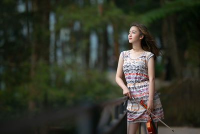 Young woman standing against trees