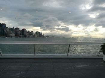 Scenic view of sea by buildings against sky during sunset